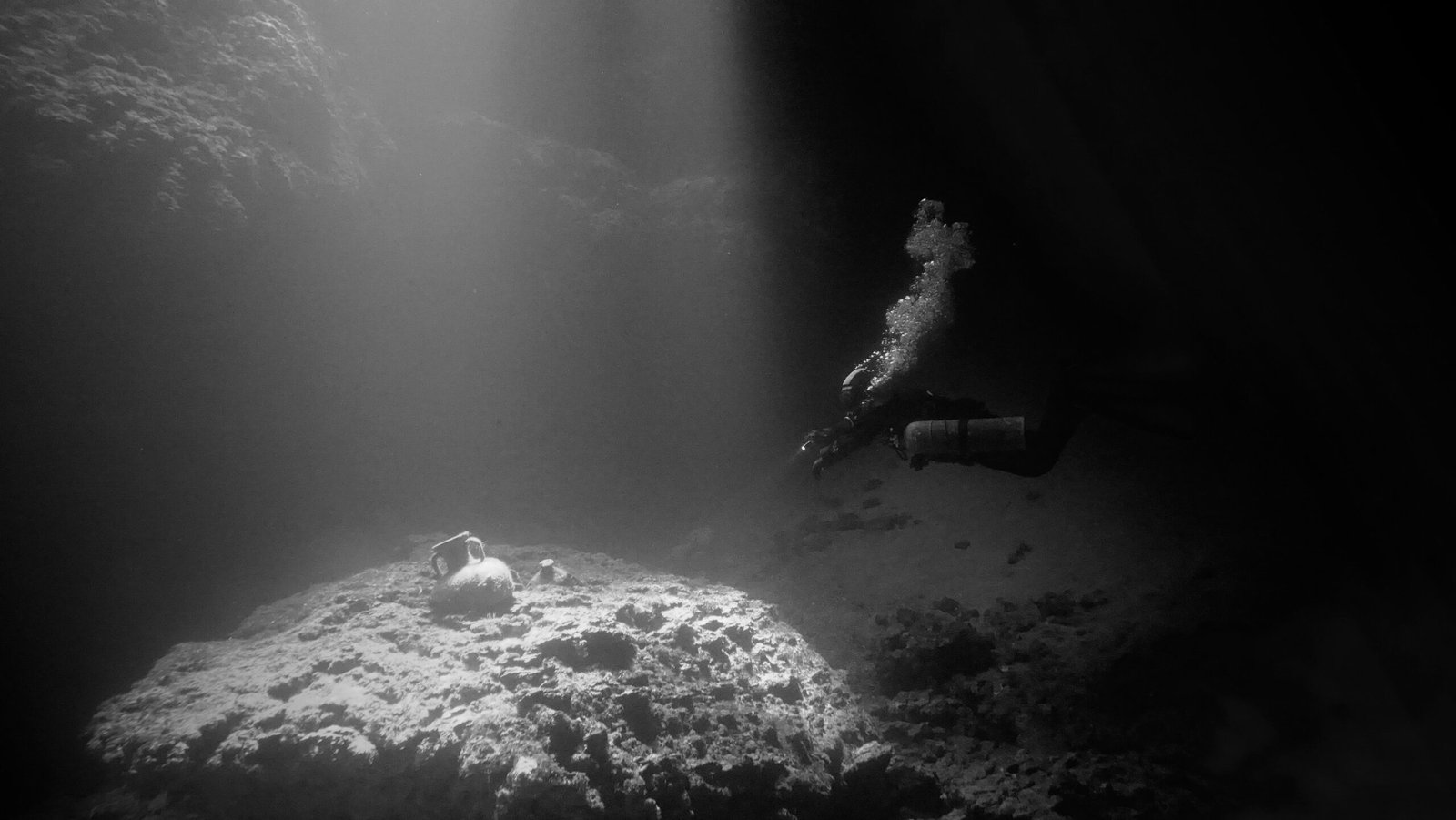 a person swimming in the water near a rock